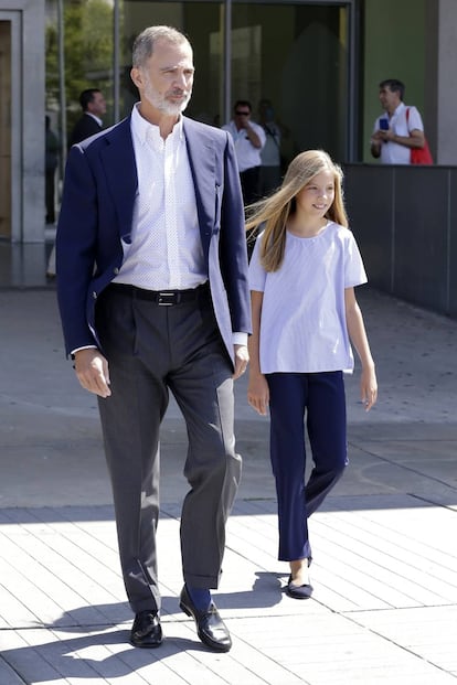 Pantalón de pinzas, chaqueta azul y camisa con microestampado durante una de sus visitas a la clínica Quirón de Madrid. Le acompaña su hija, la infanta Sofía, con el pantalón a juego con la chaqueta de él.