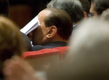 Silvio Berlusconi oculta el rostro durante una asamblea de la patronal de comerciantes.