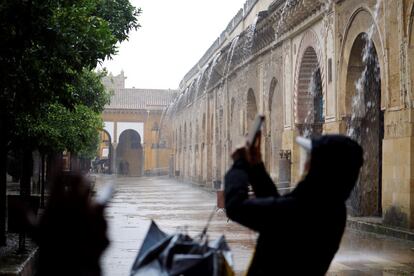 Una persona fotografía el agua que cae en el patio de los Naranjos de la Mezquita-Catedral de Córdoba, el viernes.