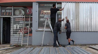 Varios hombres protegen una tienda en San Juan ante la llegada de Irma.