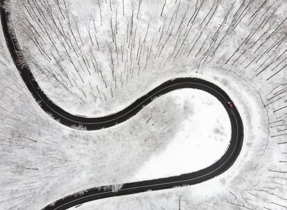 Vista aérea de un coche conduciendo por una carretera que atraviesa un bosque cubierto de nieve en Budapest (Hungría), el 18 de marzo de 2018.