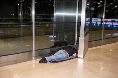 Una persona duerme en los pasillos que conectan la terminal 1 y 2 de Barajas durante la madrugada del lunes. 