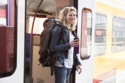 Una joven mochilera se baja de un tren.