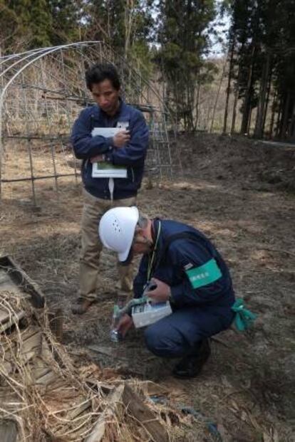 Yasushige Watanabe, un agricultor que se niega a regresar a su casa, en Miyakoji, observa cómo un técnico mide el nivel de radiación en un campo junto a su vivienda.