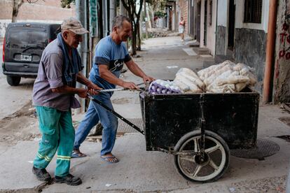 Hombres llevan alimentos a los comedores en un barrio popular de Buenos Aires.