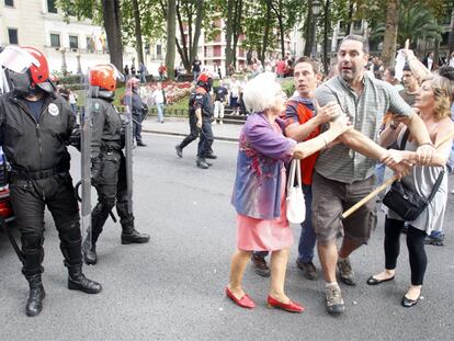 Dos mujeres sujetan a un manifestante provisto de un bastón en la marcha ilegal de Bilbao.