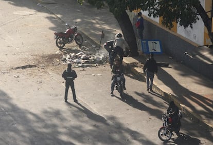 Los civiles armados y un oficial de la policía comienzan a retirar escombros de la vía pública después de reprimir a los manifestantes. 