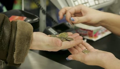 Una cajera ayuda a un cliente a contar monedas de euro en un supermercado. 