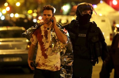 Un policía acompaña a un hombre cubierto de sangre cerca de la sala Bataclan.