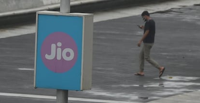 Un joven pasa junto a cartel de la empresa Jio, en la India. t