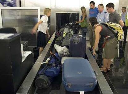 Un grupo de viajeros espera la llegada de sus maletas en una cinta transportadora en el aeropuerto de El Prat ( Barcelona) el pasado miércoles.
