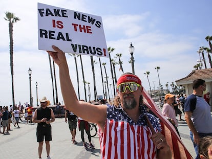 Manifestante na Califórnia levanta cartaz que diz "Fake news são os vírus de verdade", em maio.