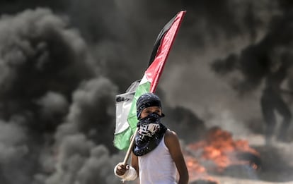 Uma criança segura a bandeira da Palestina durante os confrontos na Faixa de Gaza.