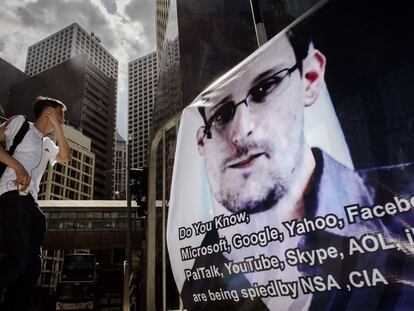 Un joven en Hong Kong pasa delante de un cartel de Edward Snowden, denunciante de espionaje por parte de la Agencia de Seguridad Nacional estadounidenses de empresas tecnológicas.
