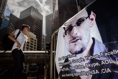 Un joven en Hong Kong pasa delante de un cartel de Edward Snowden, denunciante de espionaje por parte de la Agencia de Seguridad Nacional estadounidenses de empresas tecnológicas.