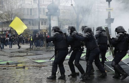 Agentes antidisturbios se protegen del lanzamiento de piedras durante las protestas de los 'chalecos amarillos' en el centro de París.