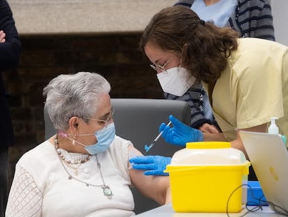 A health worker administers a third vaccine dose to a nursing home resident.