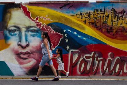 A woman and a child walk pass a mural of the late President Hugo Chávez in Caracas.