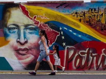 Mulher caminha em frente a um mural de Chávez.