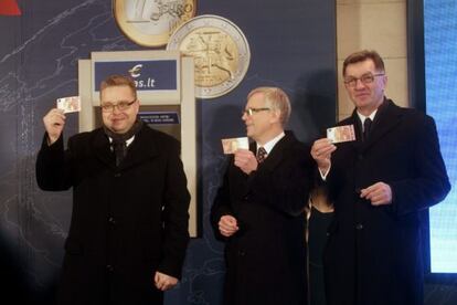 El presidente del Banco de Lituania Vitas Vasiliauskas (a la izquierda), el ministro de finanzas de Lituania Rimantas Sadzius (en el centro) y el primer ministro de Lituania Algirdas Butkevicius, tras retirar un billete de 10 euros de un cajero autom&aacute;tico en Vilnius (Lituania) este 1 de enero.
