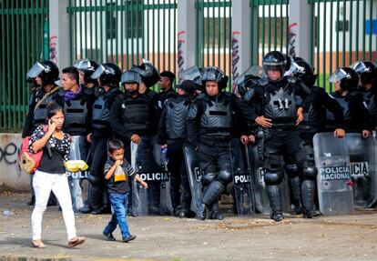 Una mujer y su hijo pasan frente a una línea de la policía antidisturbios durante una protesta contra el gobierno del presidente nicaragüense, Daniel Ortega, en Managua.