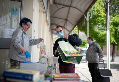 Varias familias esperan en la cola del centro de voluntario de caritas en Orcasur para recoger alimentos.