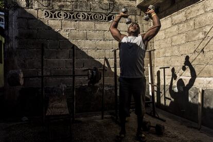 Un joven hace pesas en un gimnasio de fabricación propia. 