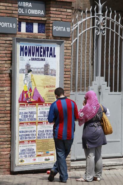 Una pareja contempla ayer el cartel anunciador de la temporada en la Monumental de Barcelona, donde este domingo habrá corrida.