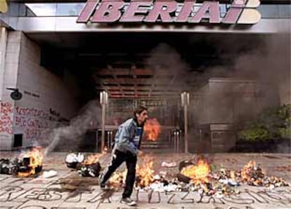 Un manifestante se aleja de los neumáticos en llamas alineados frente a la puerta de la oficina central de Iberia en Buanos Aires.
