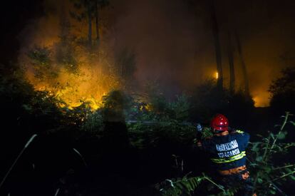 Un agente trabaja en la extinci&oacute;n del fuego declarado en Caldas, esta madrugada.