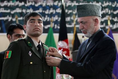 Karzai impone una medalla a un oficial afgano en la academia militar de Kabul.