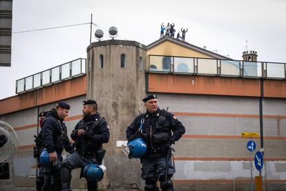 Policías italianos frente a la prisión de San Vittore de Milán. Detrás de ellos, los prisioneros protestando sobre el tejado.