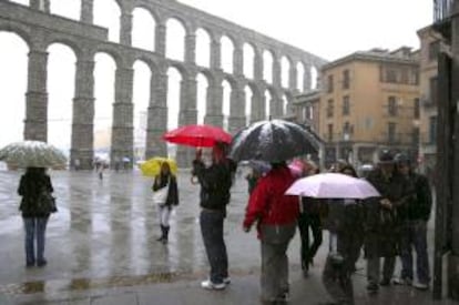 Varios turistas hacen fotografías junto al Acueducto de Segovia mientras nieva en la capital. EFE/Archivo