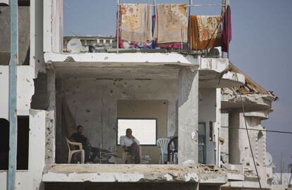 Dos palestinos sentados en una de las habitaciones de su casa en ruinas en Shijaeyih, Gaza.