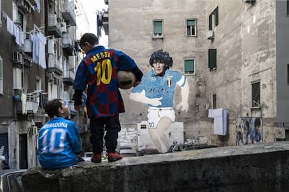 Dos ni?os con las camisetas de Messi y Maradona frente a un mural con la imagen del astro argentino en una calle de Npoles.