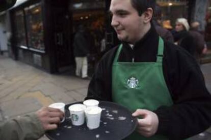 Un trabajador de un establecimiento Starbucks reparte chocolate caliente entre los viandantes en la calle Oxford Street, Londres (Reino Unido). EFE/Archivo