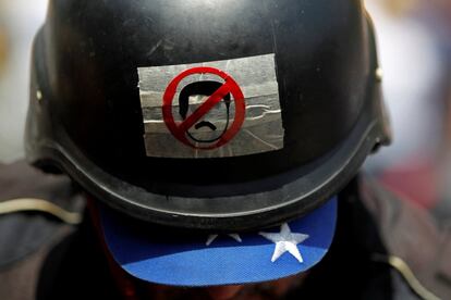 Un manifestante de la oposición venezolana lleva un casco con una pegatina que representa al presidente venezolano Nicolás Maduro durante la protesta en contra del gobierno.