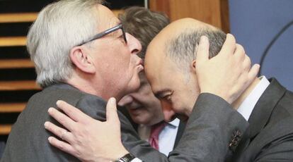 El presidente de la Comisión Europea (CE), Jean-Claude Juncker (i), besa el frente del comisario de Asuntos Económicos y Financieros, Fiscalidad y Aduanas, Pierre Moscovici (d) el 27 de junio de 2016.