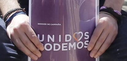 El l&iacute;der de Podemos, Pablo Iglesias, sostiene el dossier de campa&ntilde;a con el logo de Unidos Podemos.