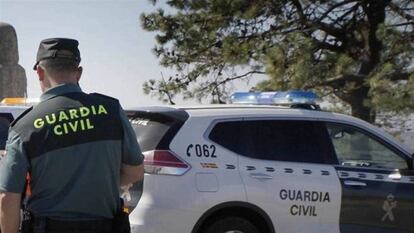 Un guardia civil delante de un coche patrulla, en una imagen de archivo. 