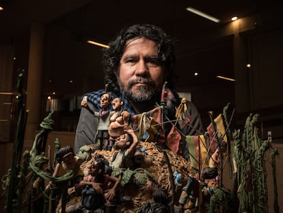 Edgar Álvarez, posa junto a una de sus obras en su exposición sobre migración, en el centro cultural Gabriel García Marquez en Bogotá, Colombia, el 3 de agosto del 2023.