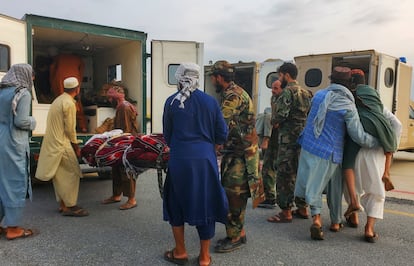 Soldados y civiles afganos meten a víctimas del terremoto a una ambulancia en el aeropuerto de Jalalabad.