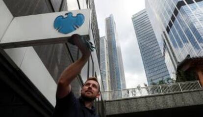 Un trabajador limpia el logo de Barclays en el distrito financiero de Londres.