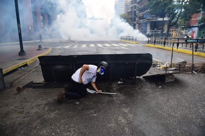 Un manifestante se protege de los botes de gas lacrimógeno que ha lanzado la policía para dispersar a los opositores del Gobierno venezolano que se concentraban contra Nicolás Maduro, en Caracas (Venezuela).
