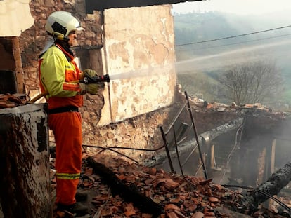 Un bombero trabaja este lunes en la zona de Sobrevega, en Grado (Asturias), donde el fuego afectó a una casa deshabitada.