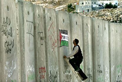 Un hombre pinta una bandera palestina en el muro de separación durante una protesta cerca de Jerusalén.