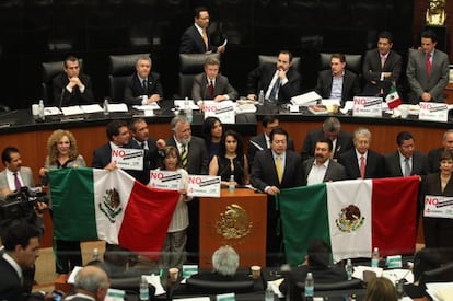 Leftist senators hold up Mexican flags to protest the energy reform during Tuesday’s debates.