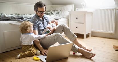 Un padre con dos ni?os mira un ordenador en su casa.