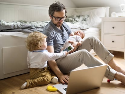 Un padre con dos niños mira un ordenador en su casa.