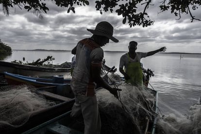 Pescadores trabajan en la laguna en los alrededores del sitio acordonado donde se ubican las excavaciones.